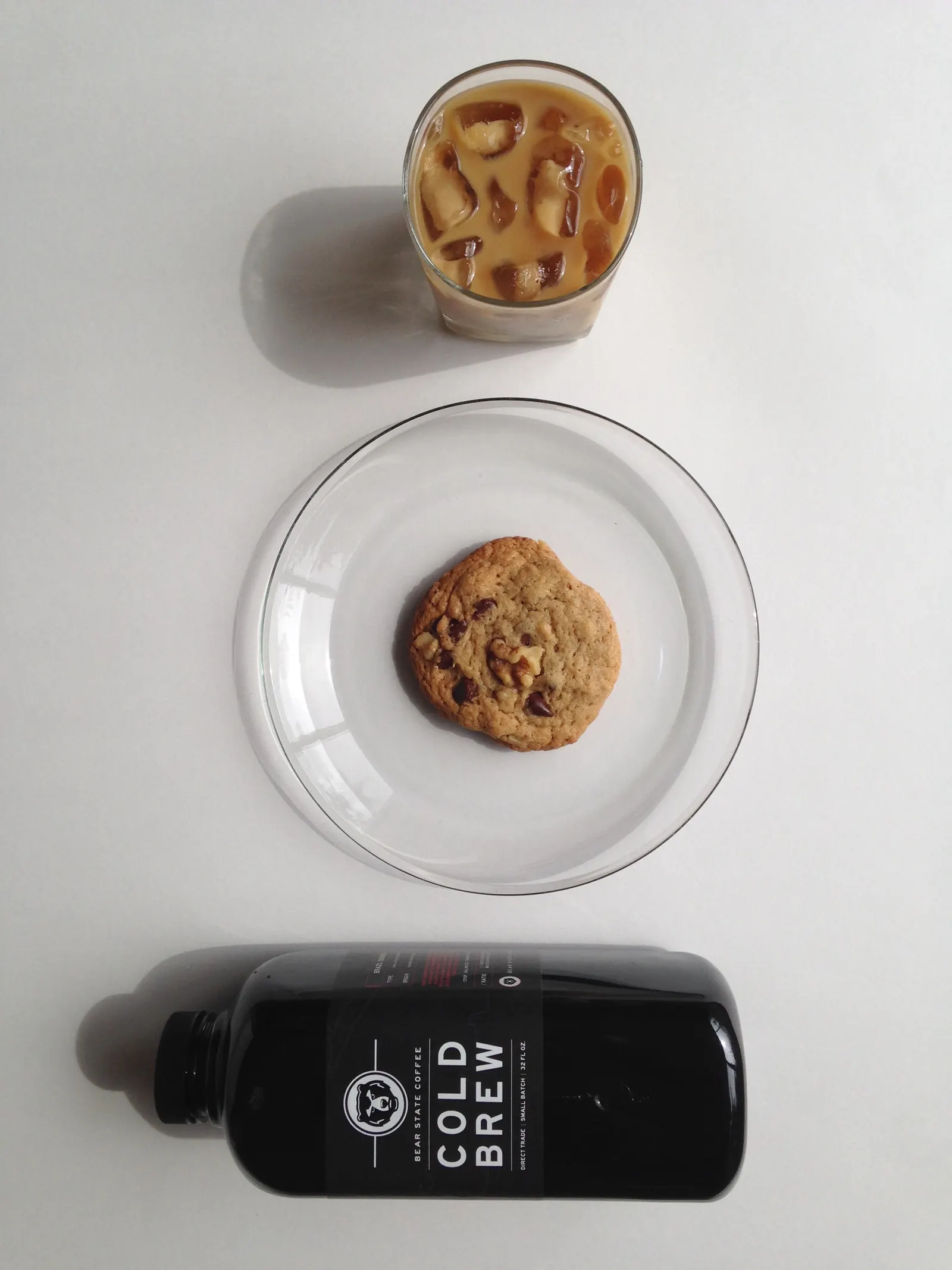 A bottle of cold brew, a glass over ice, and a cookie